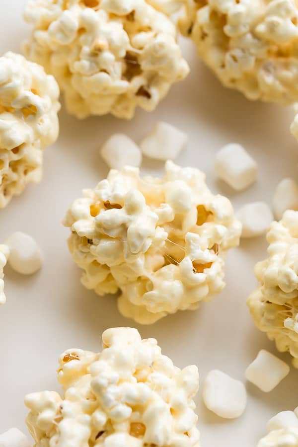 These Popcorn Balls are a fun holiday treat that the kids love! Experiment with flavors and colors to create something special for any occasion. #popcorn #christmas #holidays #recipes close up image of popcorn ball with marshmallows around
