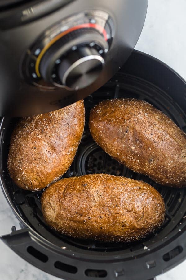 air fryer basked being pulled out of air fryer with potatoes in it