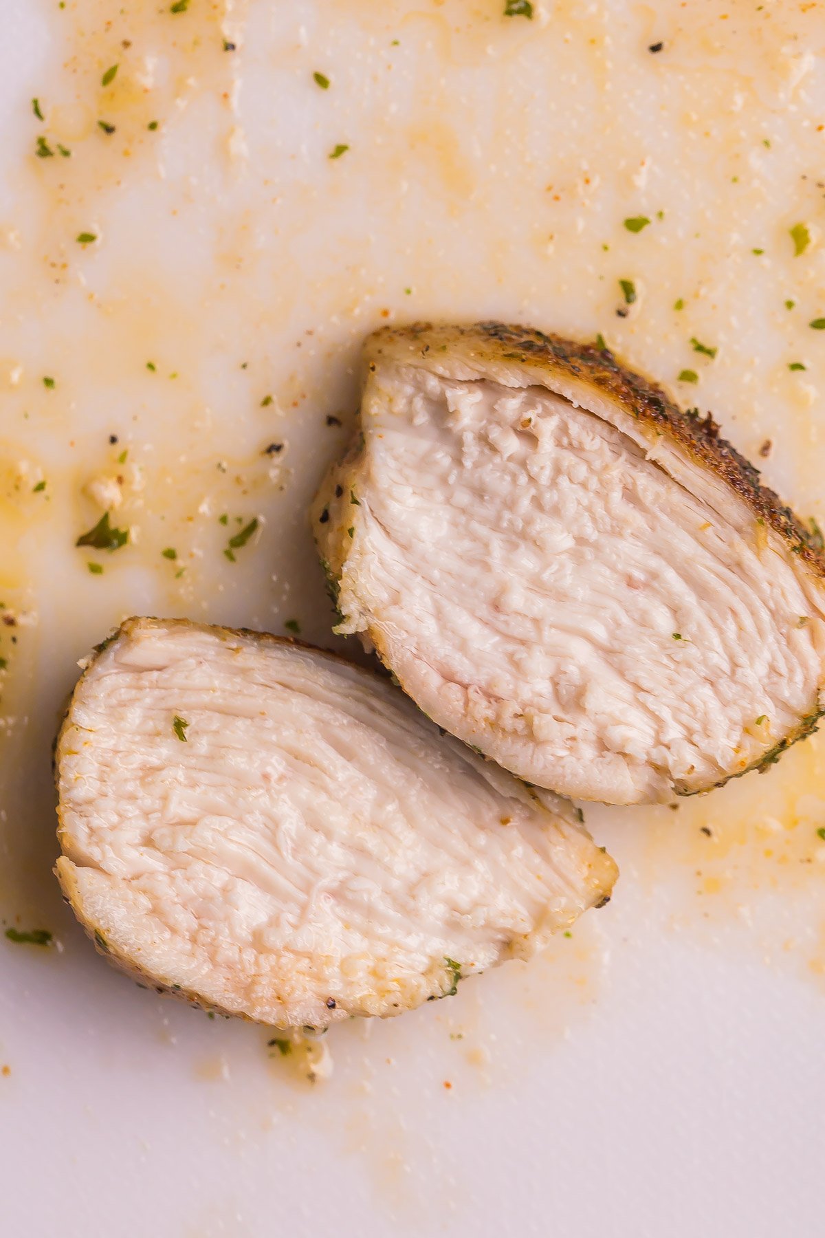 two slices of juice air fryer chicken breast on white board.