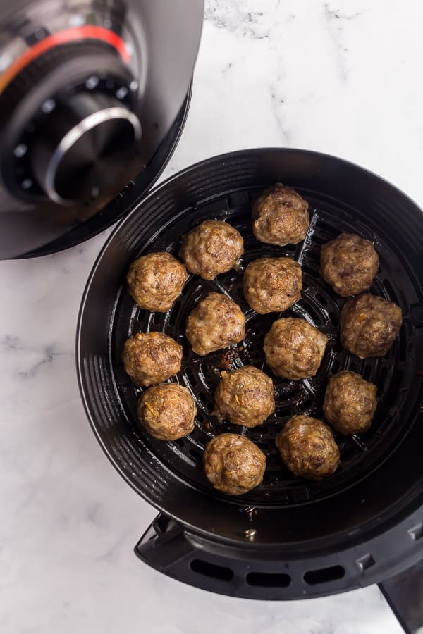 basket being pulled out of air fryer with meatballs inside