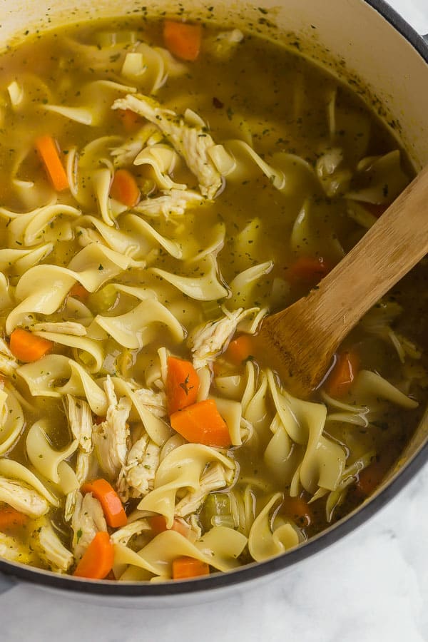 close up image of chicken noodle soup with wooden spoon in