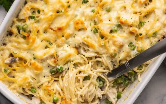 square image of chicken tetrazzini recipe in a white baking dish with scoop.