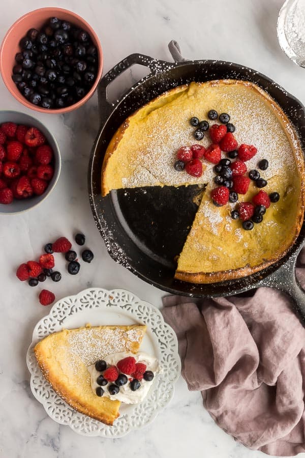 overhead image of dutch baby in skillet with one slice on plate