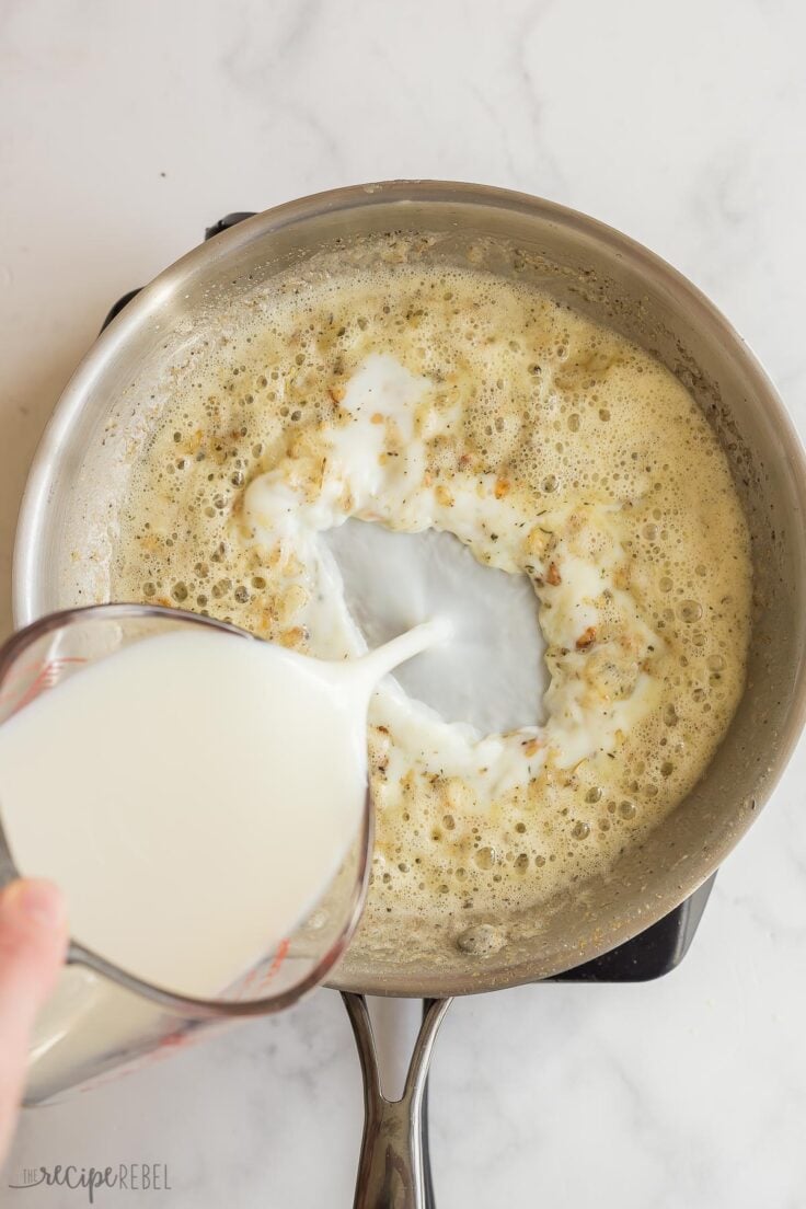 milk being added to roux in stainless steel skillet