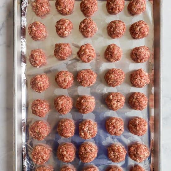 overhead image of raw meatballs on a sheet pan