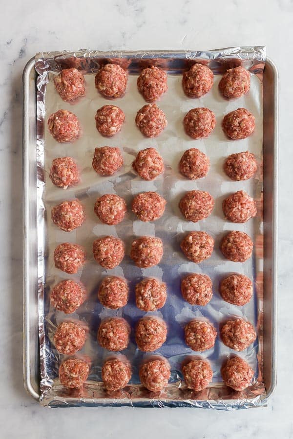 overhead image of raw meatballs on a sheet pan