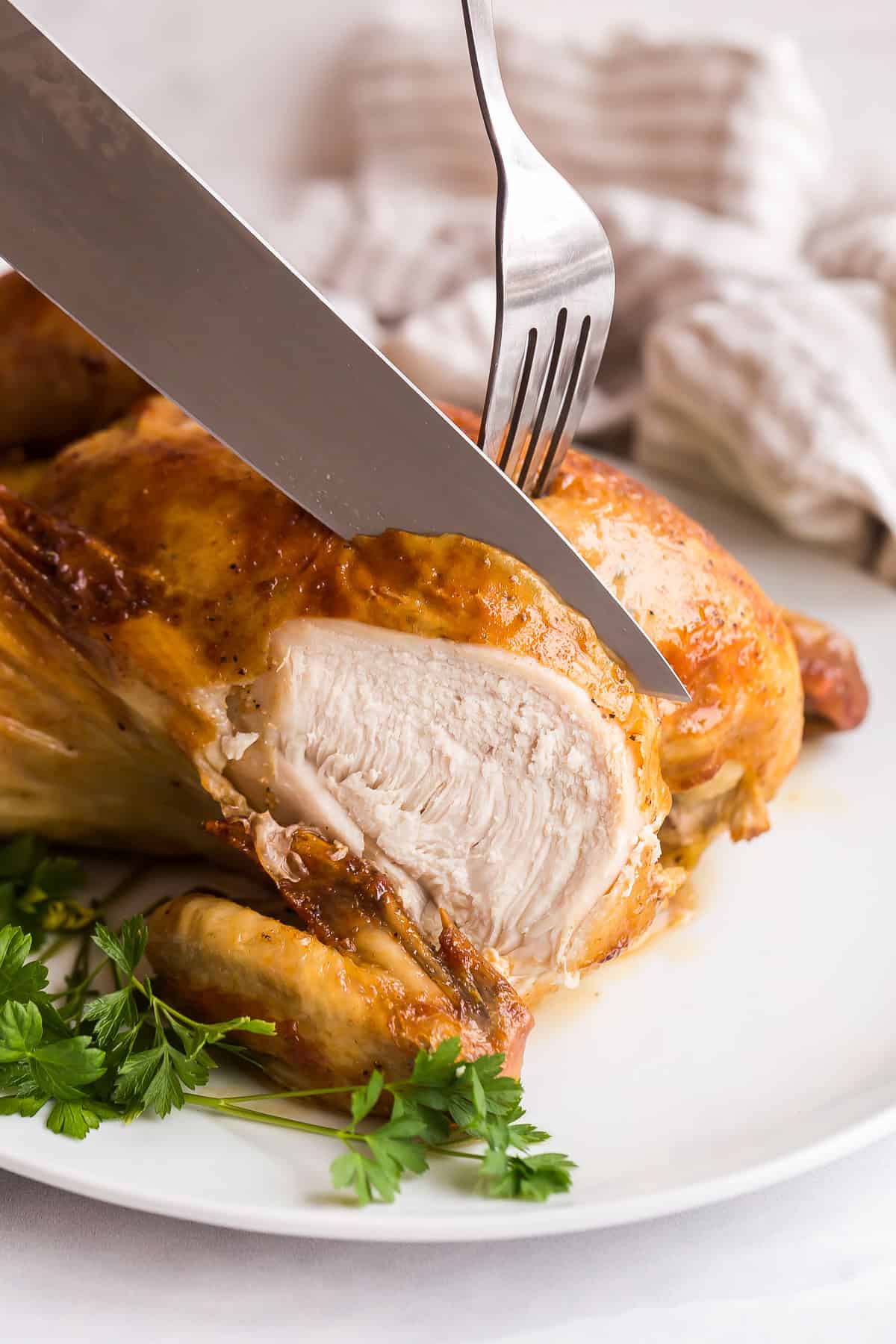 knife and fork being used to cut into roasted chicken.