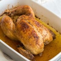 close up image of whole chicken in roasting pan