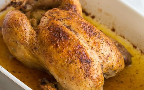 close up image of whole chicken in roasting pan