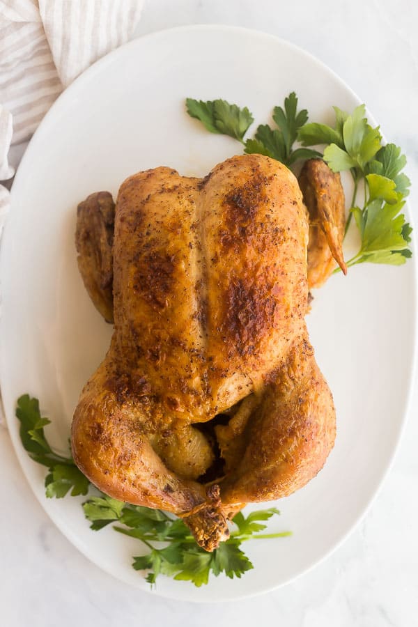 overhead image of whole roast chicken on white platter