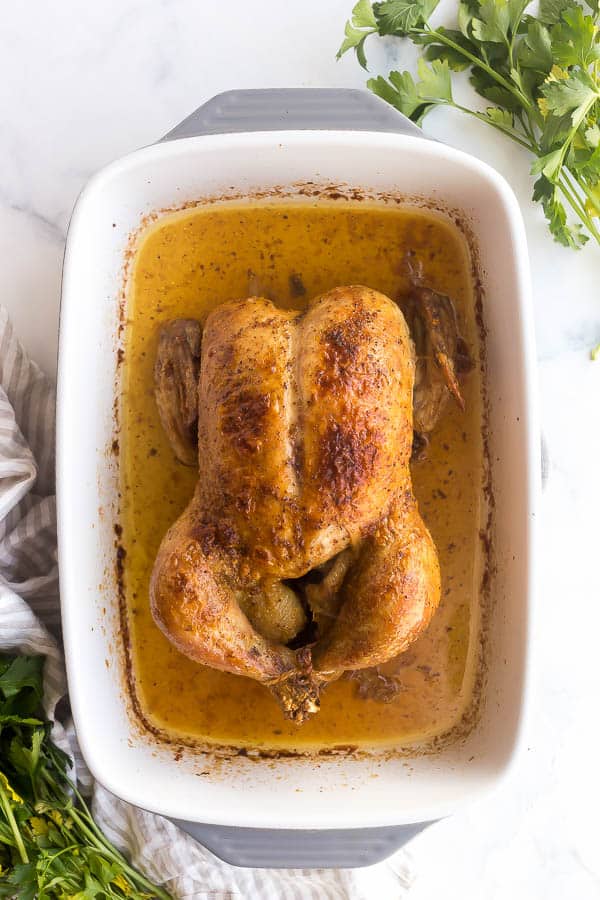 overhead image of roast chicken in grey baking dish