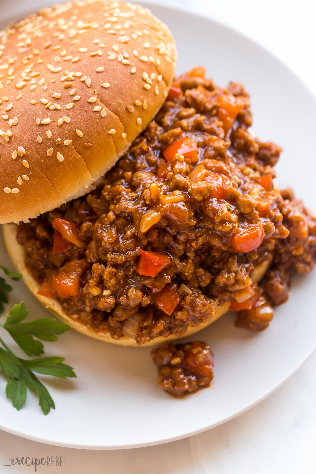 overhead image of sloppy joes recipe on a bun on white plate
