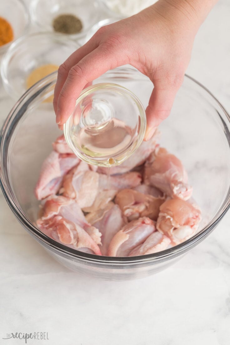 oil being poured onto uncooked chicken wings