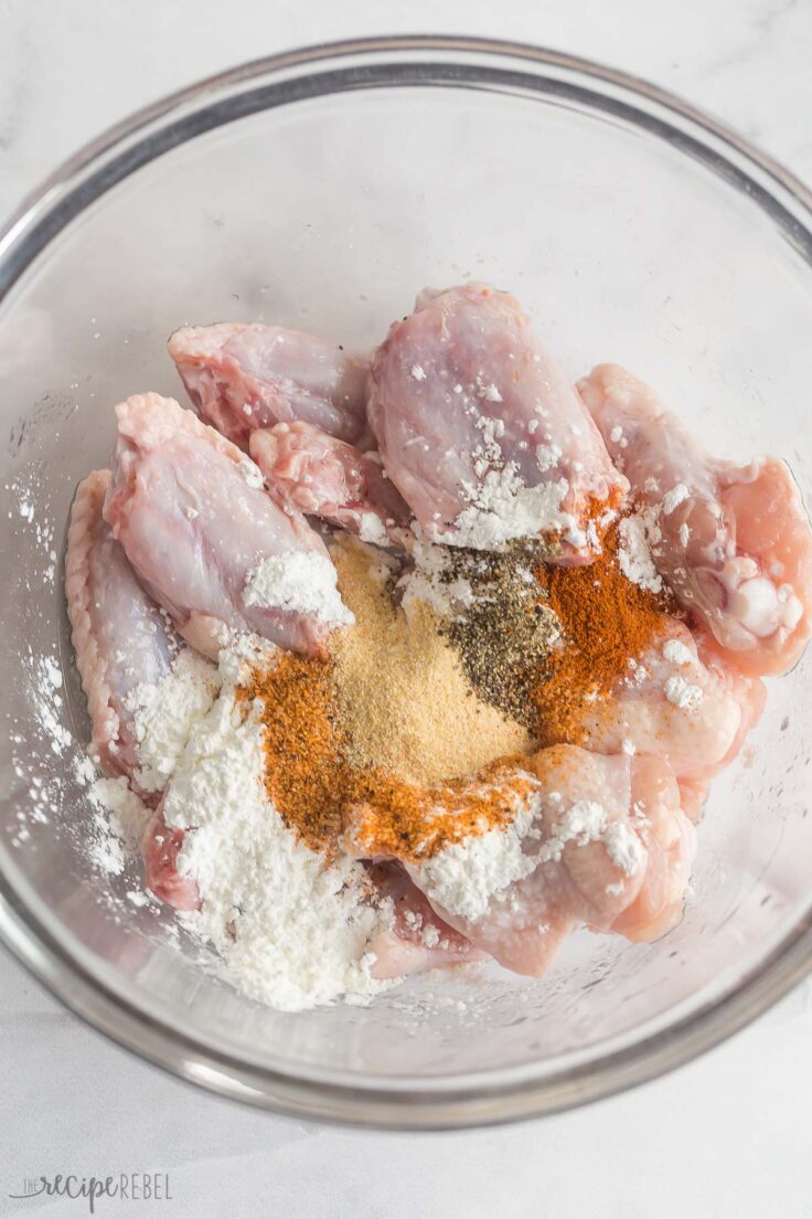 corn starch and seasonings added to bowl with chicken wings