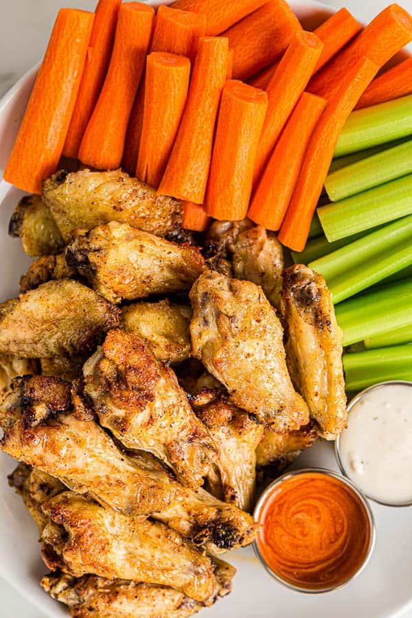 overhead image of cooked chicken wings with vegetables