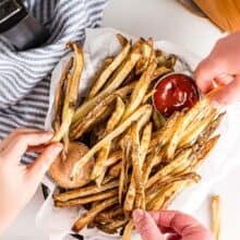overhead image of hands grabbing air fryer french fries