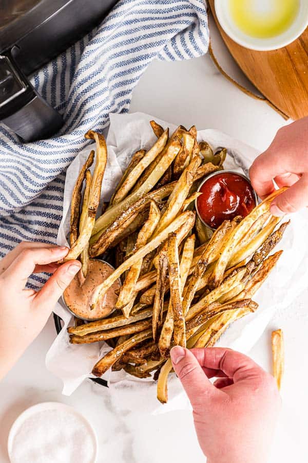 overhead image of hands grabbing air fryer french fries