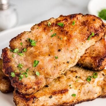 close up of air fryer pork chops with parsley sprinkled on top