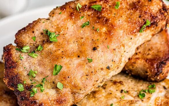 close up of air fryer pork chops with parsley sprinkled on top