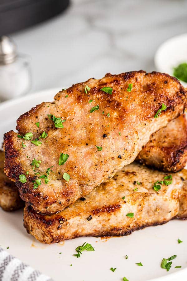 close up of air fryer pork chops with parsley sprinkled on top