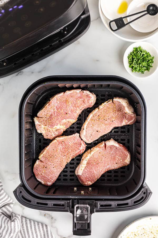 uncooked pork chops in air fryer basket