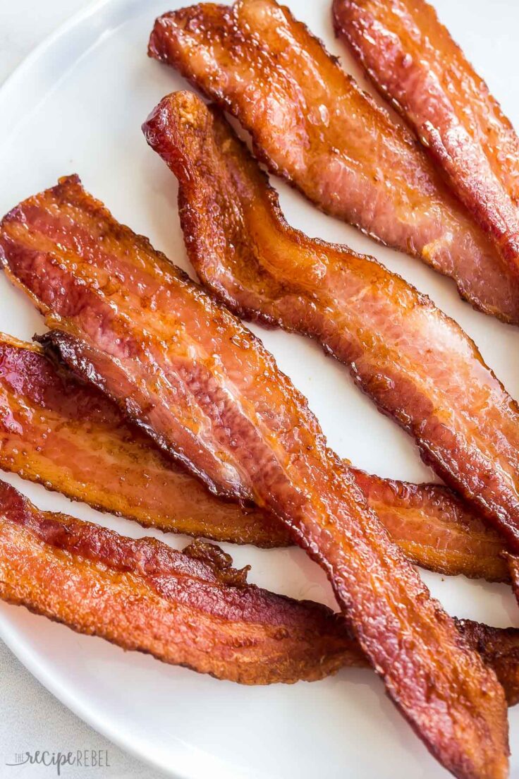 close up image of crispy air fryer bacon on white plate on white background