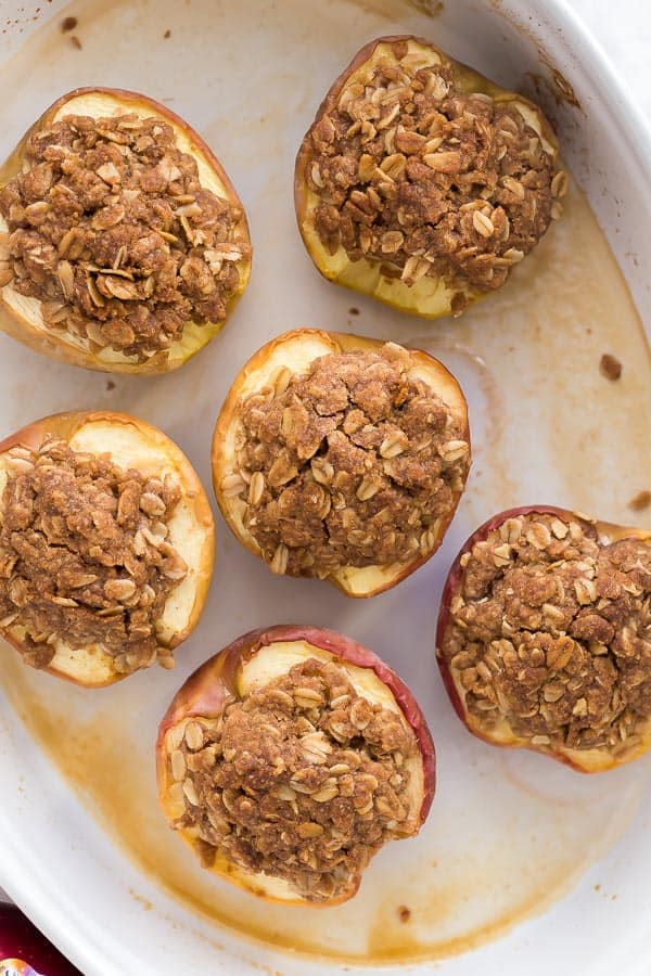 Baked Apples are topped with a brown sugar oat crumble and baked until tender - top with a scoop of ice cream or some vanilla Greek yogurt for a fun breakfast treat! #apples #dessert #baking #recipes overhead image of halved baked apples with streusel
