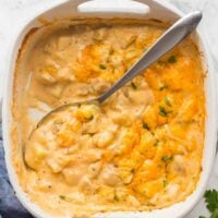 overhead image of cheesy potatoes in white casserole dish with spoon