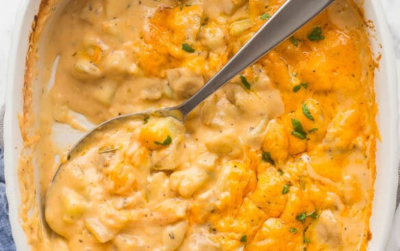 overhead image of cheesy potatoes in white casserole dish with spoon