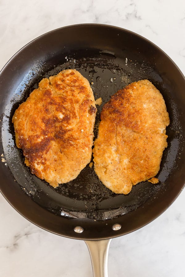 crispy browned chicken breasts in black pan