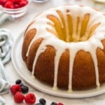 square image of lemon bundt cake with lemon glaze and berries around.