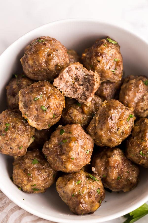 close up image of meatballs with one bite out of one meatball