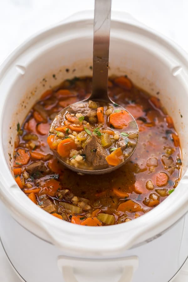 ladle scooping beef barley soup from crockpot