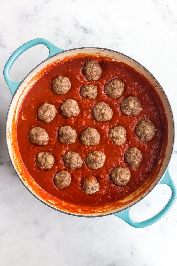 overhead image of meatballs placed in tomato sauce in large pan