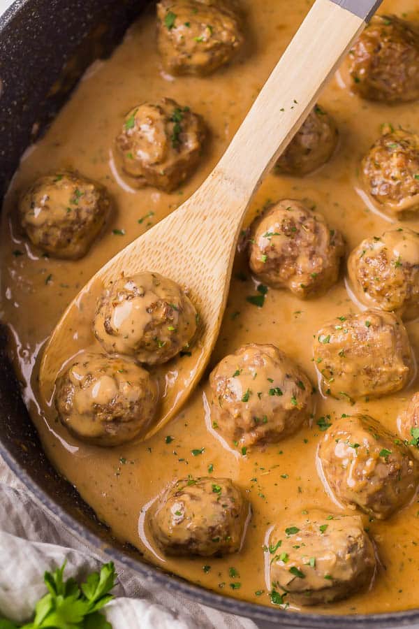 close up image of swedish meatballs in pan with wooden spoon