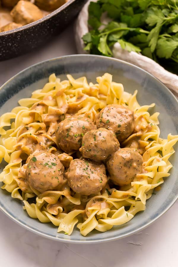 close up image of swedish meatballs on a plate of egg noodles