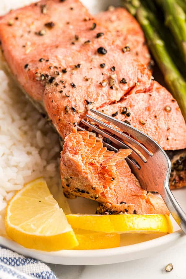 close up image of salmon flaking with fork