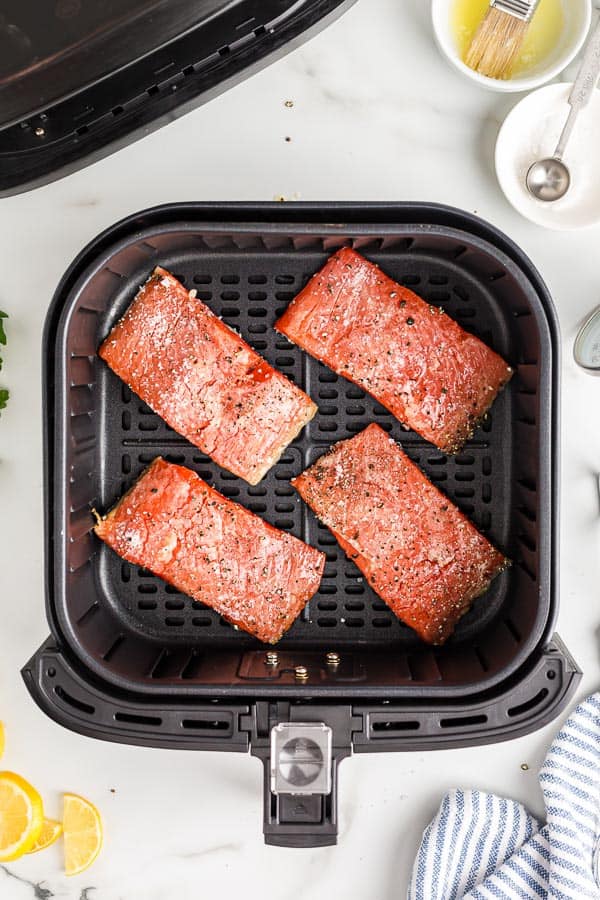 uncooked salmon fillets in air fryer basket