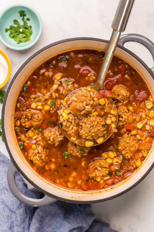 Albondigas Soup is a Mexican style meatball soup made with homemade meatballs, rice and vegetables in a spiced tomato-based broth. It's healthy and delicious one pot meal! #soup #meatball #dinner overhead image of albondigas soup in large dutch oven