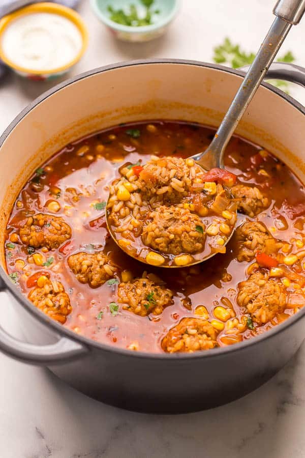 metal ladle scooping meatball soup from pot