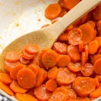 close up of glazed carrots in pan with wooden spoon
