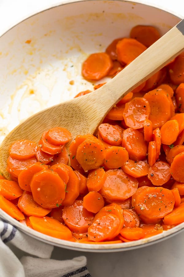 close up of glazed carrots in pan with wooden spoon