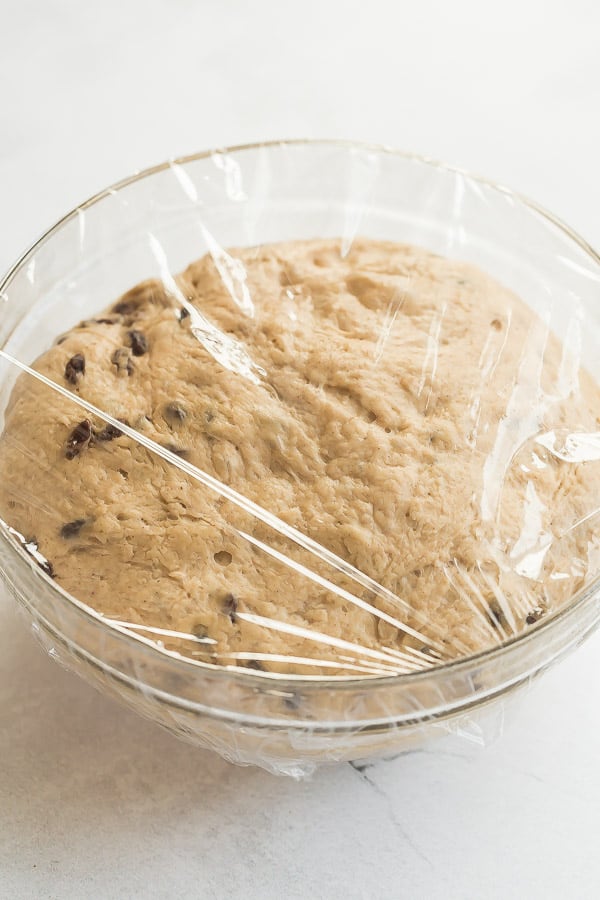 hot cross bun dough in glass bowl after rising