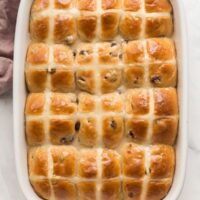 overhead image of hot cross buns in white baking dish with glaze