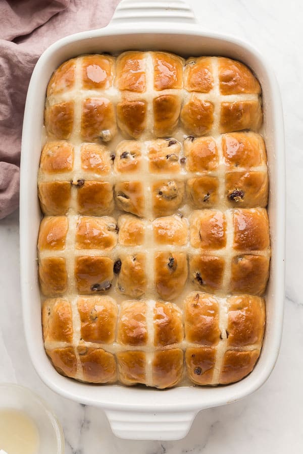 overhead image of hot cross buns in white baking dish with glaze