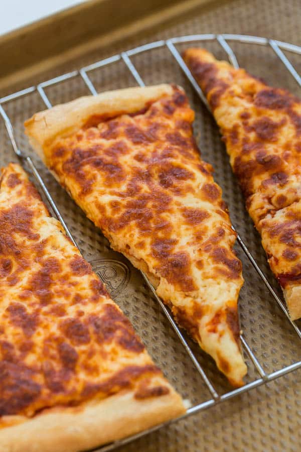 close up image of pizza slice on rack on sheet pan