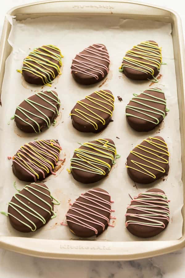 peanut butter eggs with colored chocolate drizzle on sheet pan