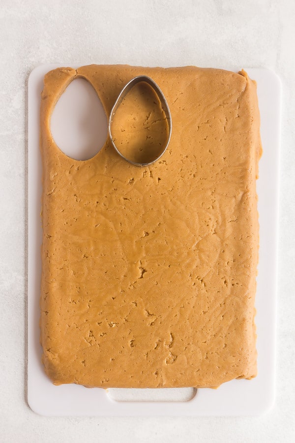using a cookie cutter to cut eggs out of peanut butter