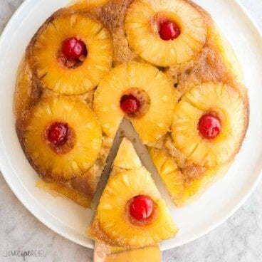 square image of pineapple upside down cake with slice being removed.