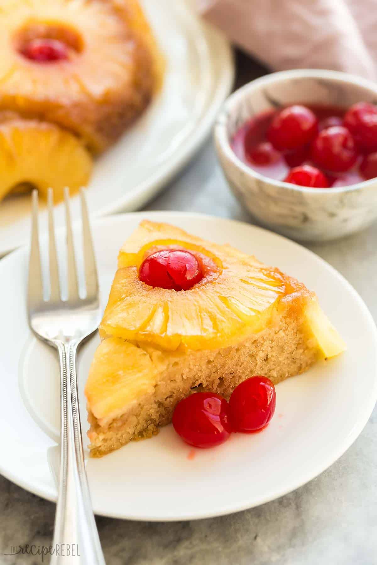 This easy Pineapple Upside Down Cake from scratch is a retro dessert made with one bowl and a whisk! It has brown sugar caramelized pineapple rings, a moist vanilla cake and maraschino cherries. #cake #dessert #recipe | dessert recipes | pineapple dessert | spring dessert | easter cake | easter dessert | fruit dessert | easy cake recipes | easy recipes piece of pineapple upside down cake on white plate with fork.
